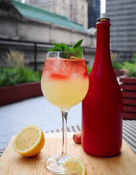 Original LYONS shop photograph of the matte red bottle beside a citrus cocktail
